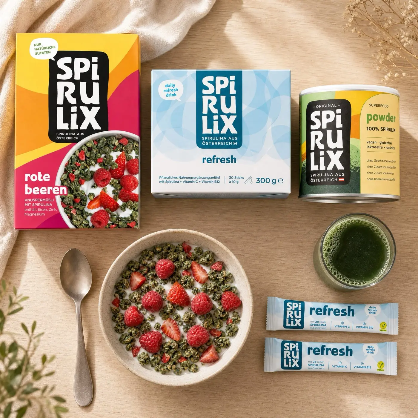 Overhead breakfast table with SPIRULIX Rote Beeren, Refresh and Powder beside a bowl and green drink